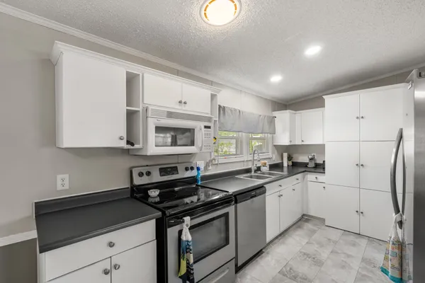 a kitchen with stainless steel appliances granite countertop a sink stove refrigerator and cabinets