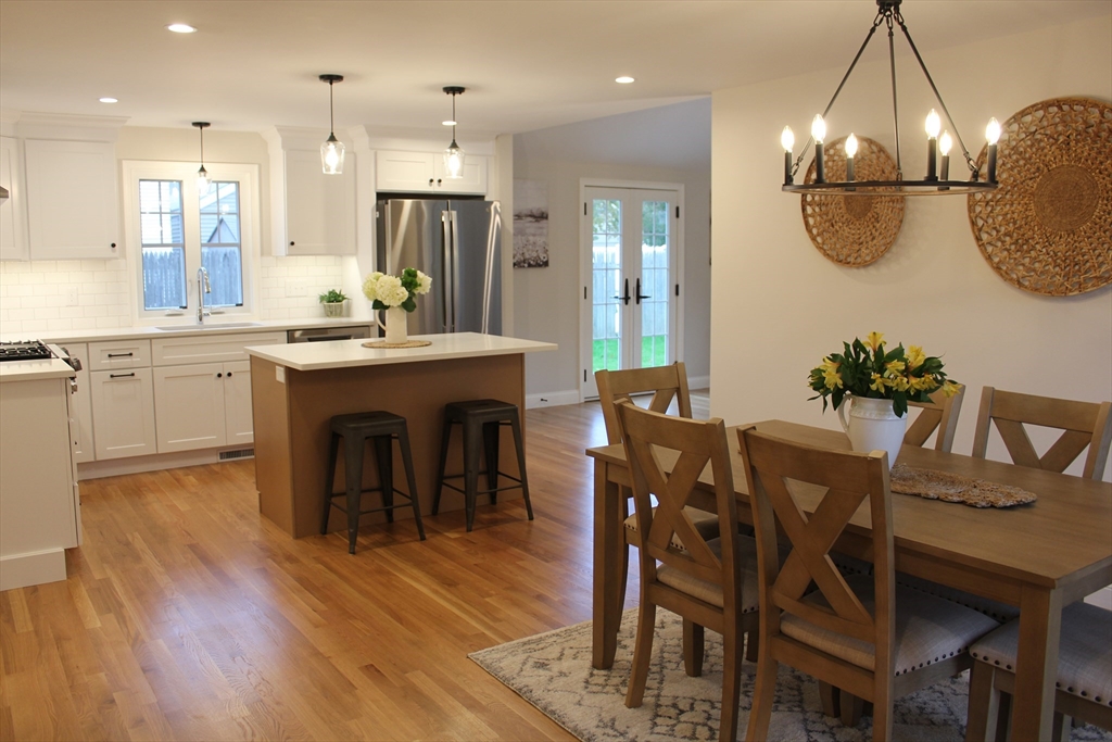 30 Maple Street Hudson, MA 01749 - Photo 12 of 36 a kitchen with stainless steel appliances kitchen island granite countertop a dining table chairs and white cabinets