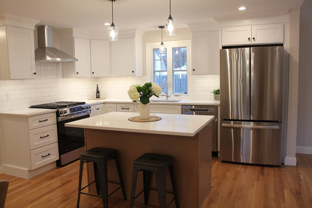 30 Maple Street Hudson, MA 01749 - Photo 7 of 36 a kitchen with stainless steel appliances a refrigerator a sink a stove a dining table and chairs