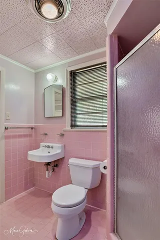 a bathroom with a toilet a sink a mirror and a window