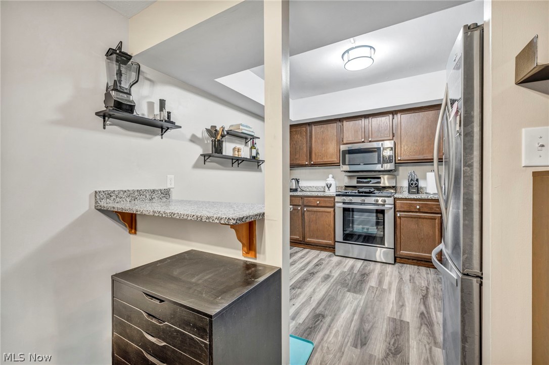 22952 Mastick Road, Unit 203 Cleveland, OH 44126 - Photo 12 of 35 Kitchen with a kitchen bar, appliances with stainless steel finishes, light stone counters, and light hardwood / wood-style flooring