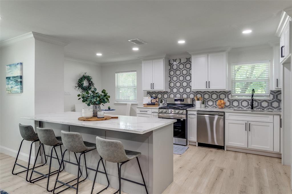 a kitchen with white cabinets a sink stove and white stainless steel appliances