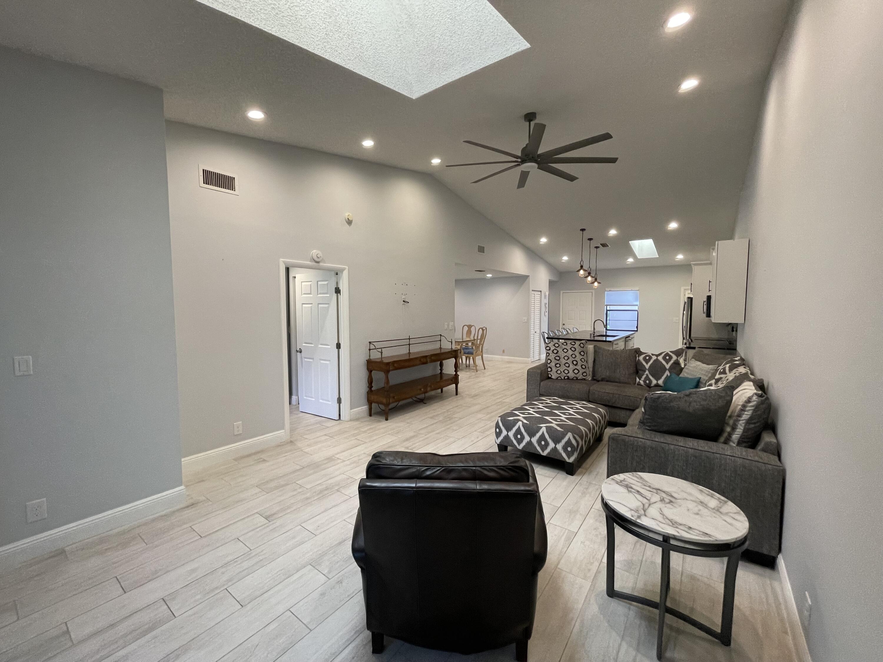 6157 Sunny Pointe Circle Delray Beach, FL 33484 - Photo 14 of 64 a living room with furniture and a dining table with wooden floor