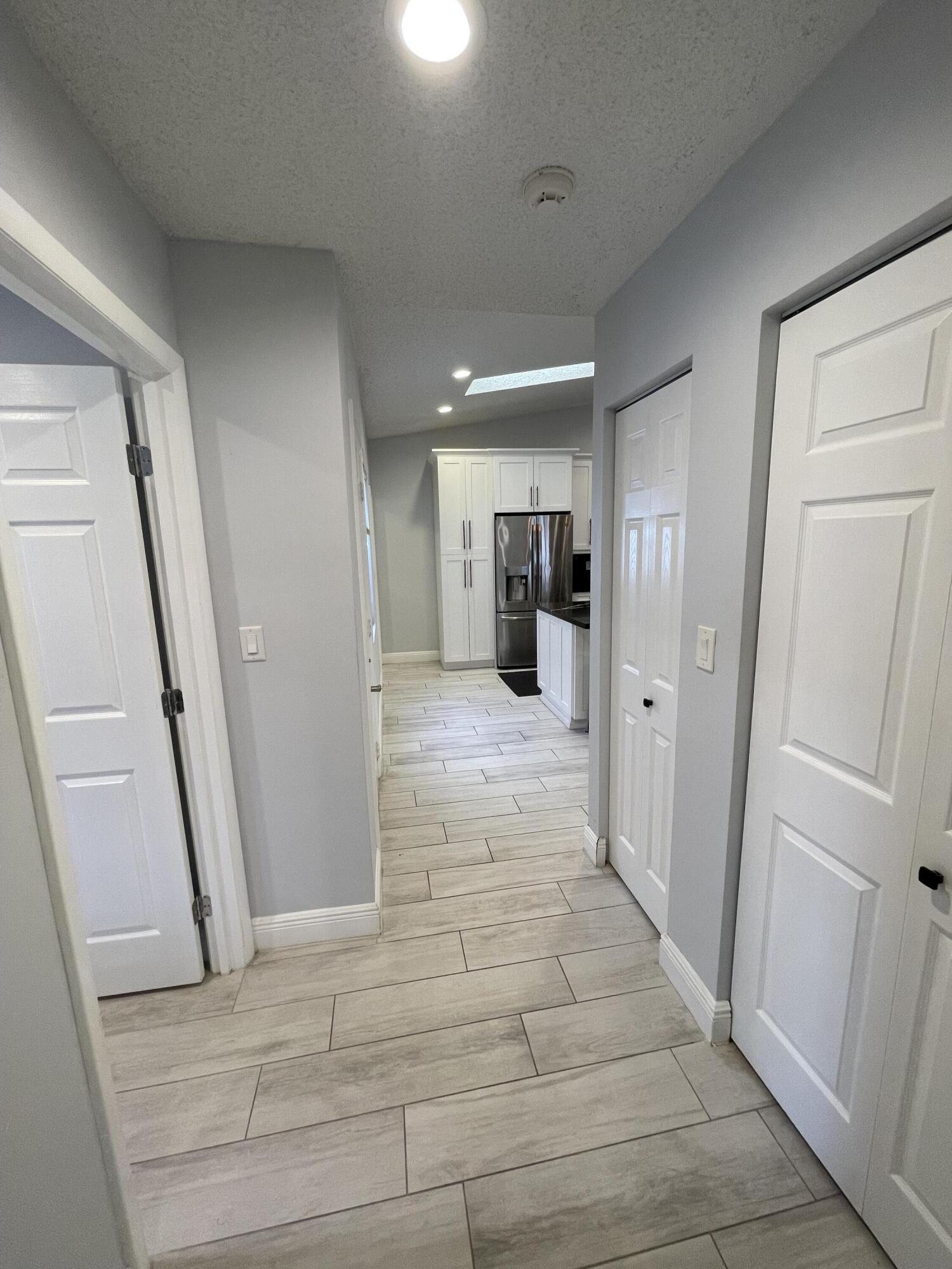 6157 Sunny Pointe Circle Delray Beach, FL 33484 - Photo 25 of 64 a view of a hallway with wooden floor and a living room