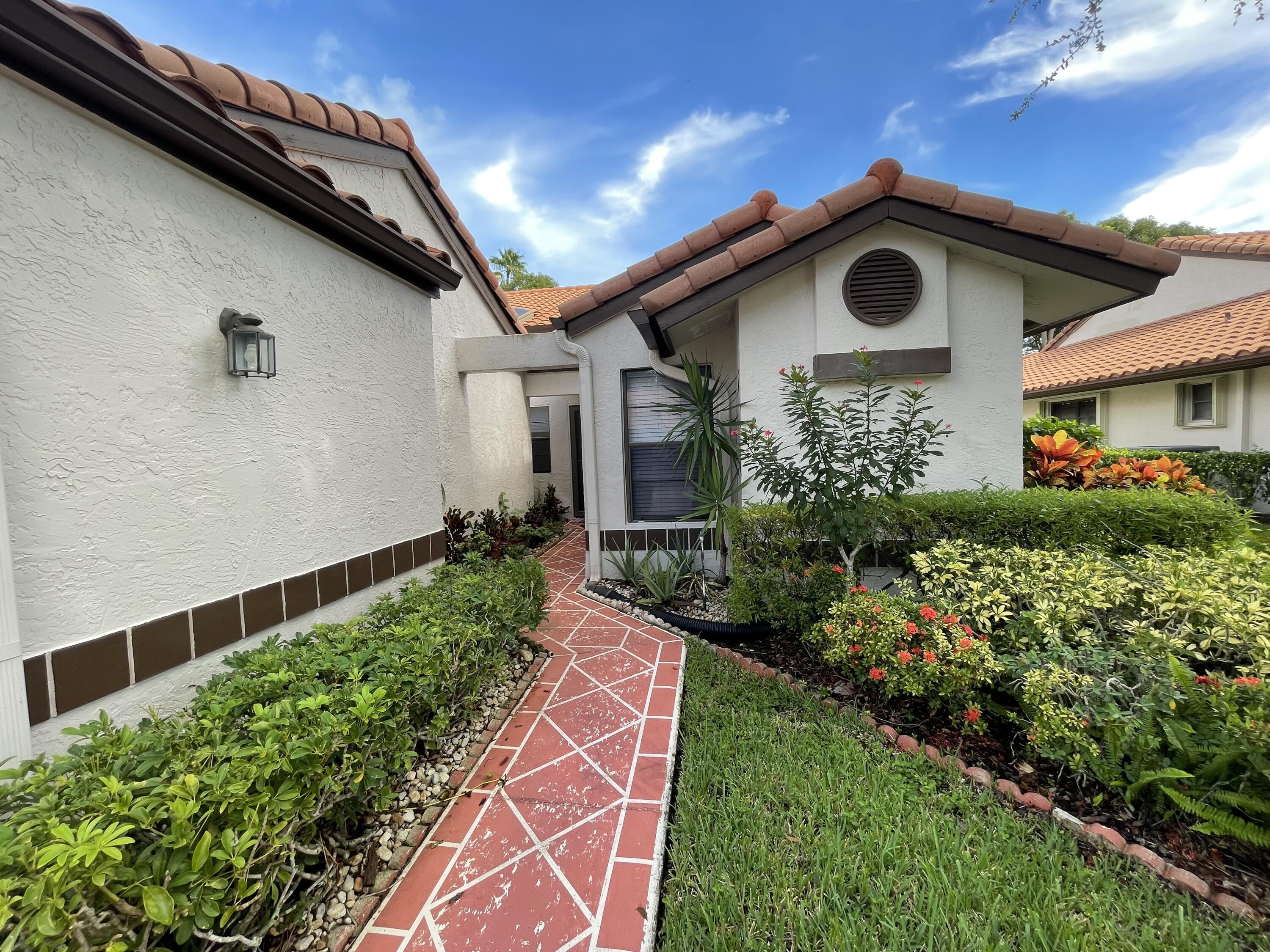 6157 Sunny Pointe Circle Delray Beach, FL 33484 - Photo 40 of 64 a front view of a house with a yard
