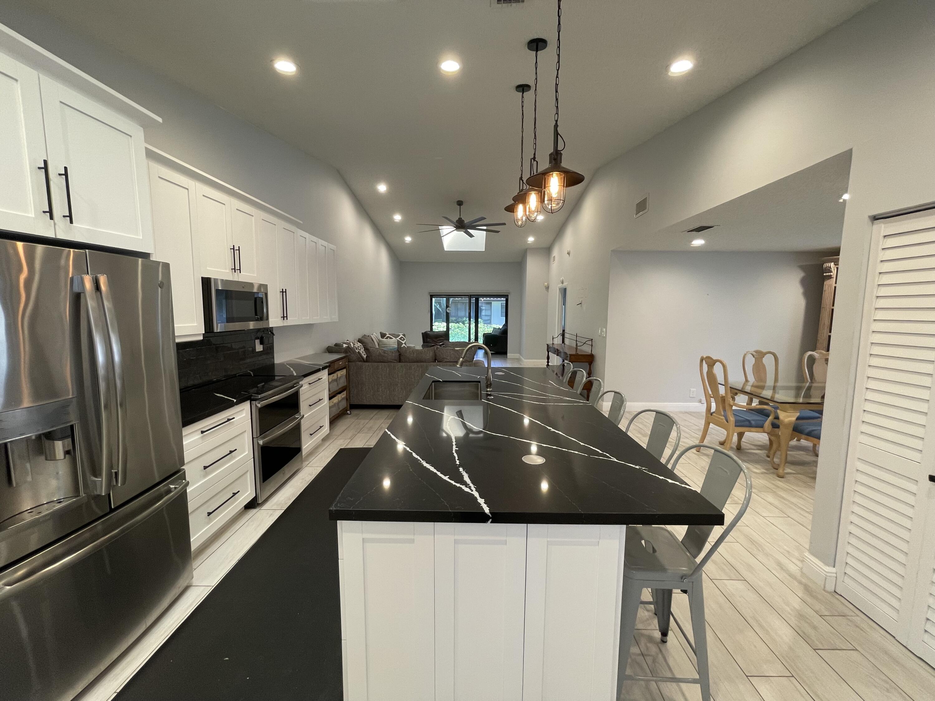 6157 Sunny Pointe Circle Delray Beach, FL 33484 - Photo 4 of 64 a kitchen with a sink a counter space stainless steel appliances and cabinets