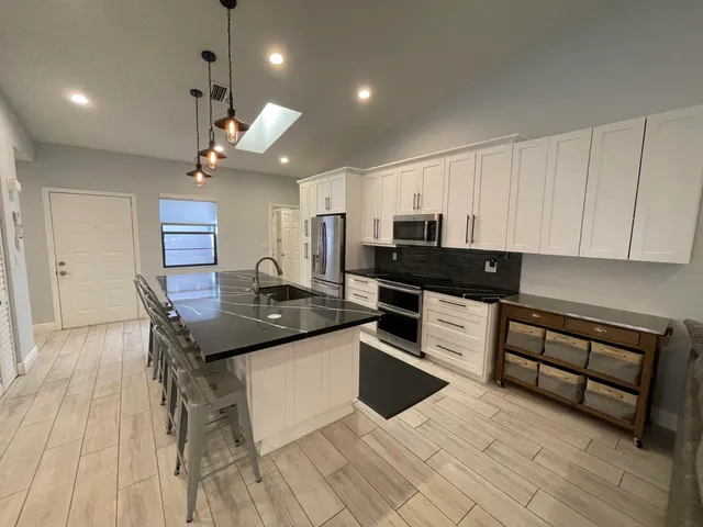 a kitchen with stainless steel appliances granite countertop a sink a stove and refrigerator