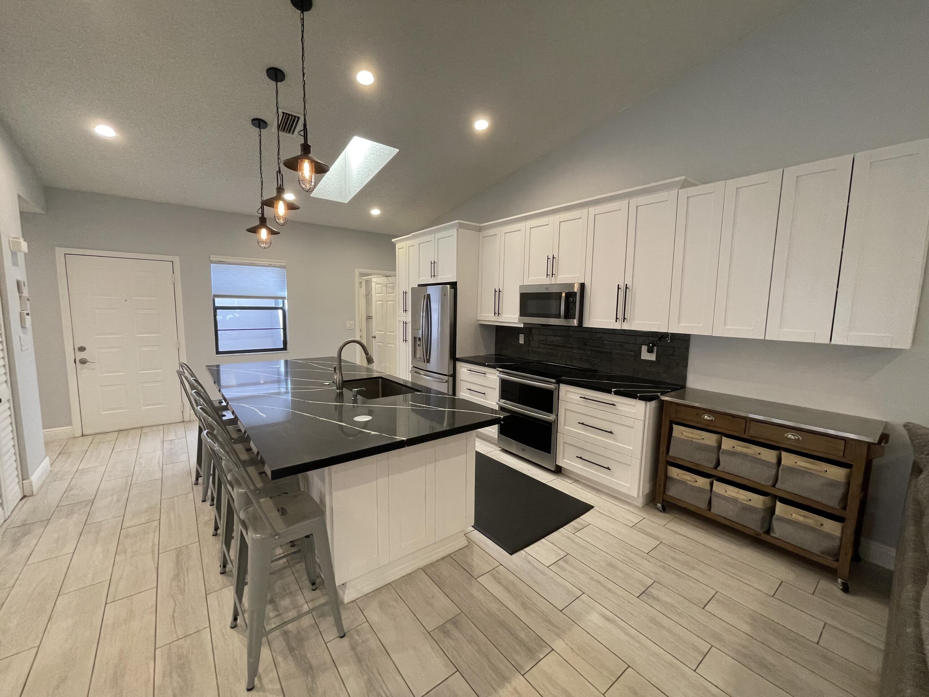 6157 Sunny Pointe Circle Delray Beach, FL 33484 - Photo 8 of 64 a kitchen with stainless steel appliances kitchen island granite countertop a sink and cabinets