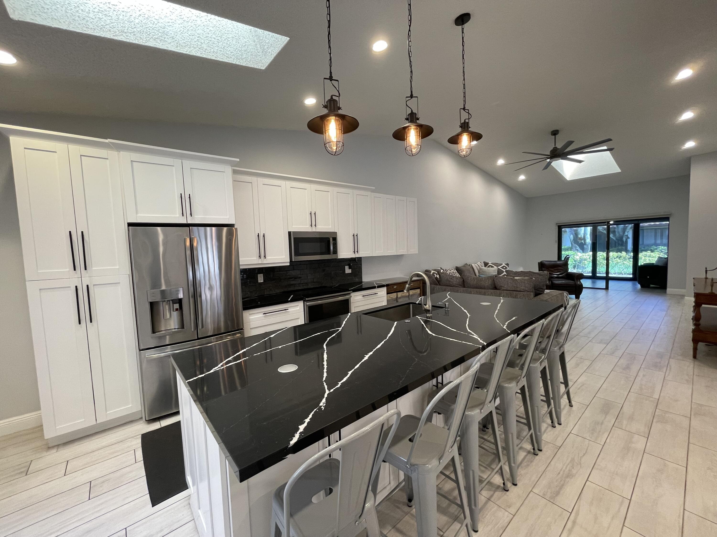 6157 Sunny Pointe Circle Delray Beach, FL 33484 - Photo 9 of 64 a kitchen with stainless steel appliances granite countertop a sink a stove and refrigerator