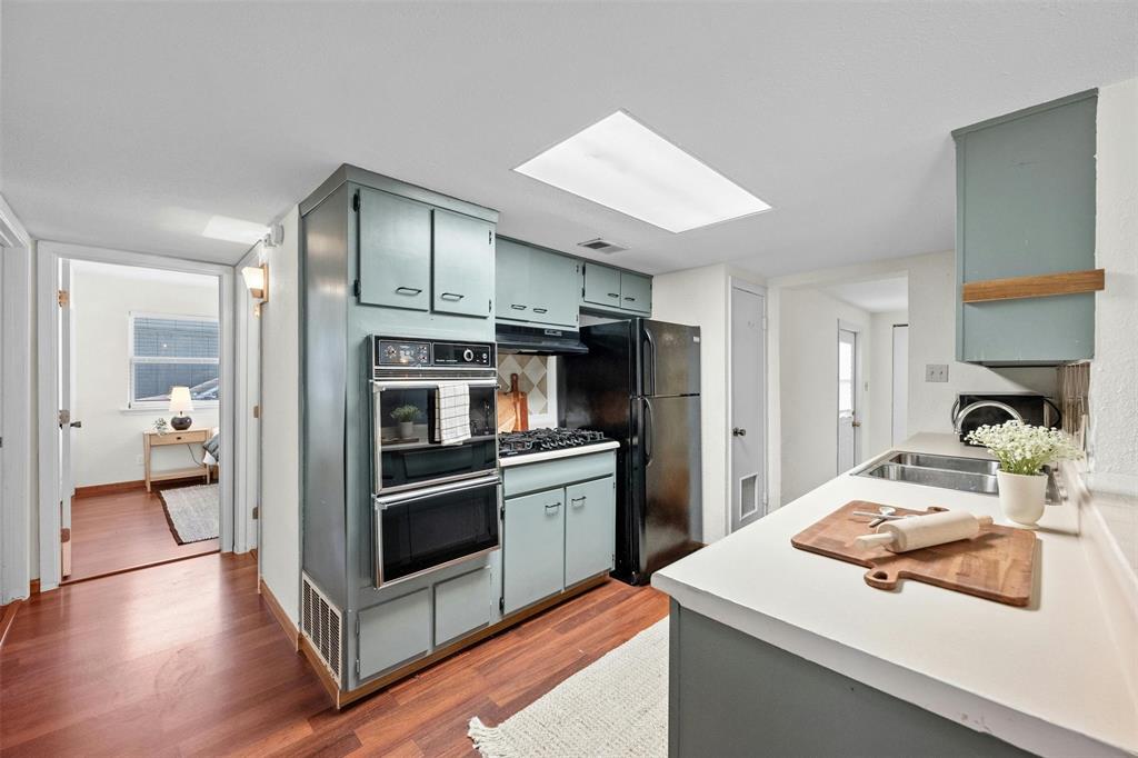 4610 South 1st Street Austin, TX 78745 - Photo 13 of 23 Kitchen with black appliances, wood finished floors, a skylight, light countertops, and under cabinet range hood