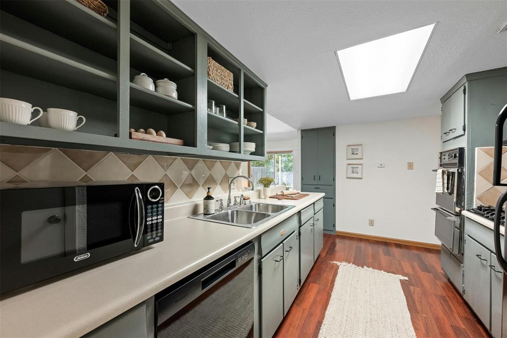 4610 South 1st Street Austin, TX 78745 - Photo 15 of 23 Kitchen with a sink, black appliances, a skylight, a warming drawer, and dark wood finished floors