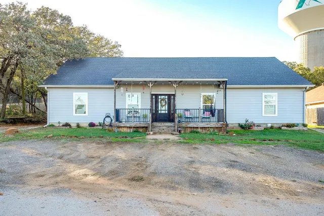 a view of a house with a yard and large tree