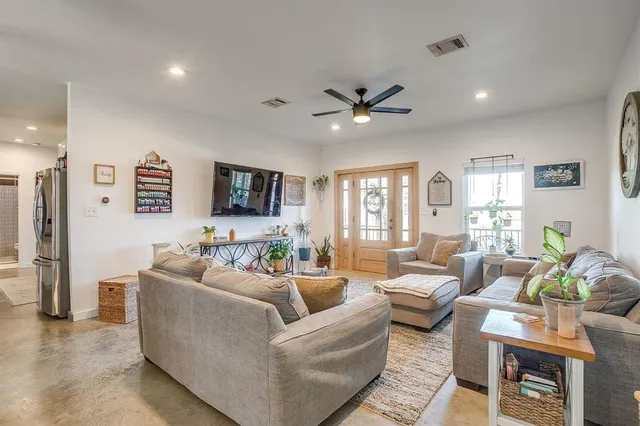 a living room with furniture a ceiling fan a flat screen tv and a window