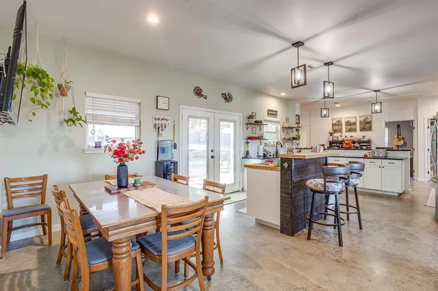 a dining room with kitchen island stainless steel appliances furniture a chandelier and kitchen view