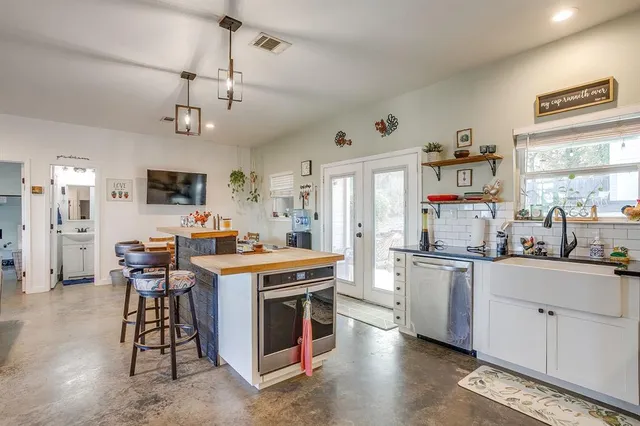 a kitchen with stainless steel appliances a stove a sink dishwasher a refrigerator and white cabinets with wooden floor