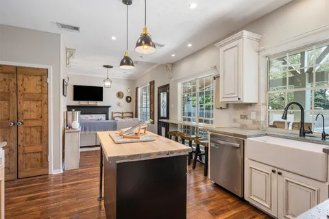 a kitchen with a refrigerator a stove top oven a sink dishwasher and white cabinets with wooden floor