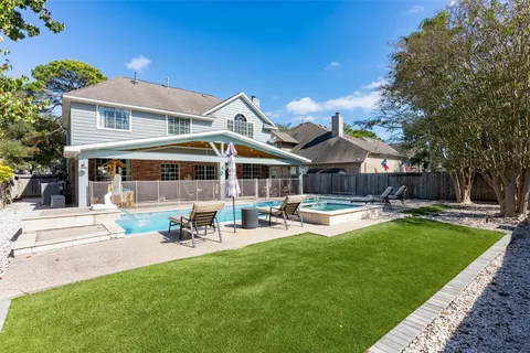 a view of a white house with a yard and lawn chairs under an umbrella