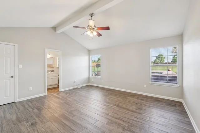 an empty room with wooden floor chandelier fan and windows