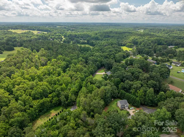 an aerial view of residential houses with outdoor space and trees