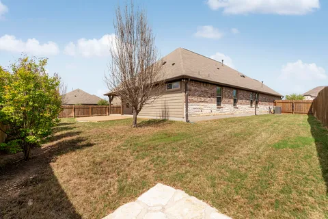 a view of a house with backyard and tree