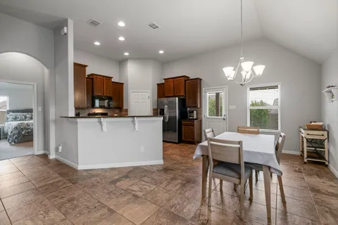 a kitchen with stainless steel appliances granite countertop a stove top oven a sink dishwasher and a refrigerator with wooden cabinets