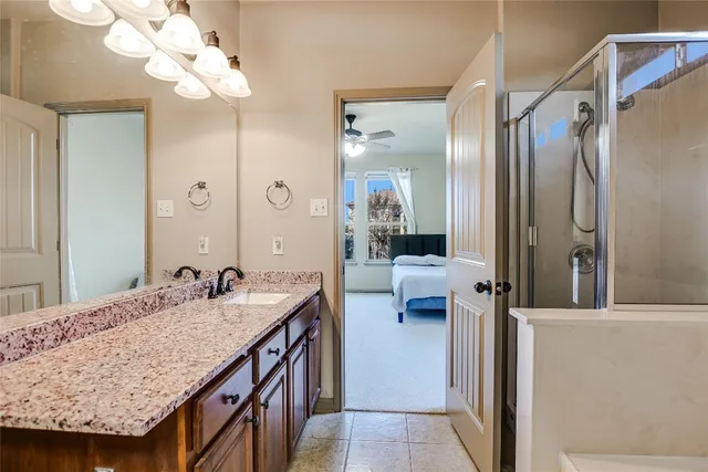 a en suite bathroom with a granite countertop sink a mirror and a shower