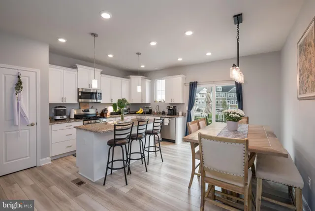 a kitchen with kitchen island wooden floors appliances and white cabinets