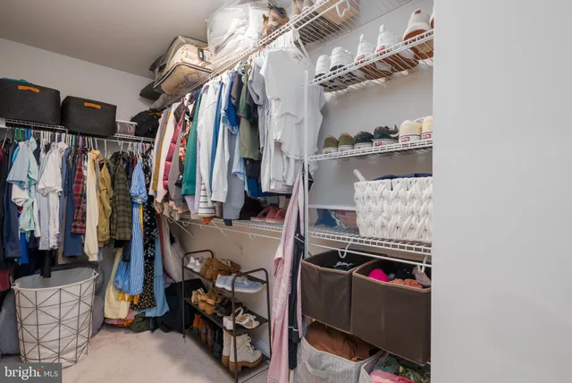 a view of walk in closet with clothes and shoes