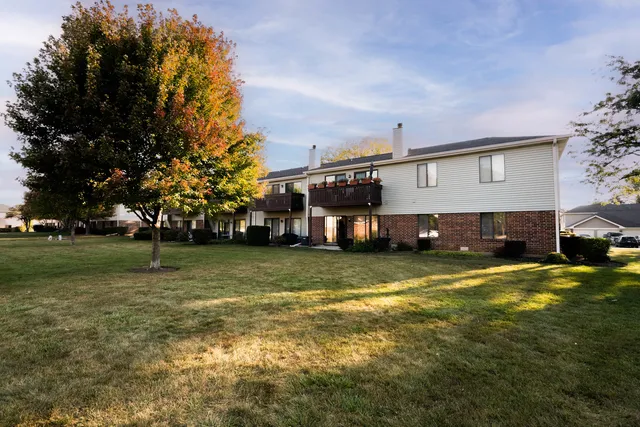 a view of a big house with a big yard and large trees