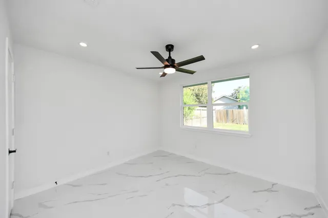 an empty room with a window and a ceiling fan