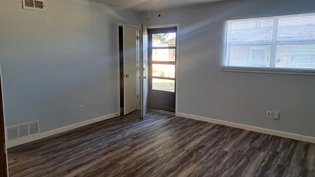 an empty room with wooden floor and windows