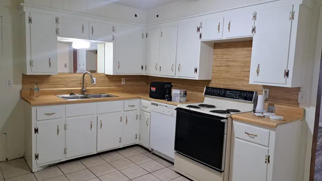 a kitchen with granite countertop white cabinets and white appliances
