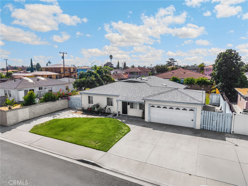 14721 Riata Street Midway City, CA 92655 - Photo 2 of 37 a view of a white house next to a yard with plants and brick wall
