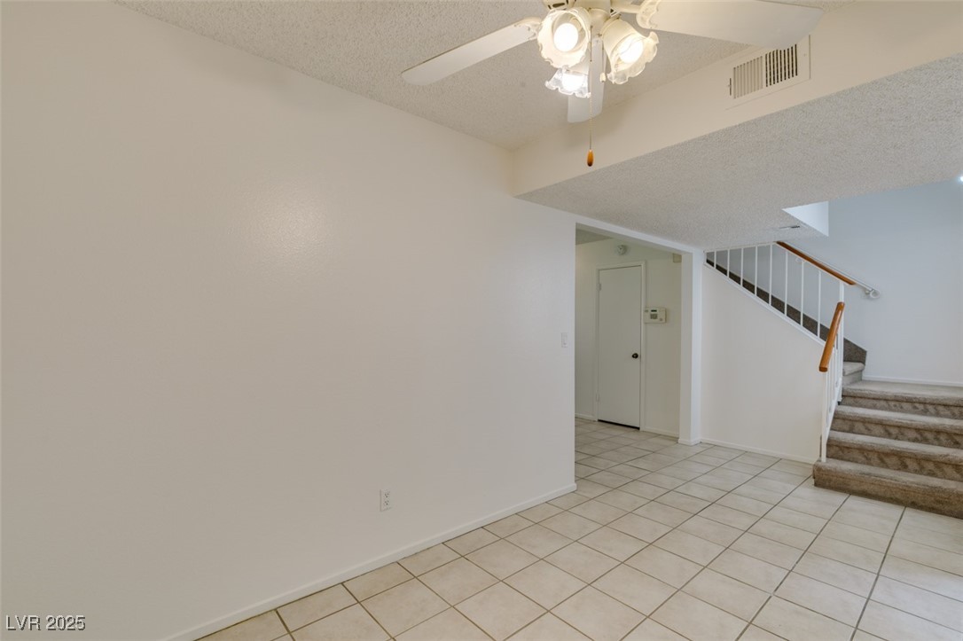 2681 Ruthe Duarte Avenue Las Vegas, NV 89121 - Photo 18 of 43 Spare room with visible vents, light tile patterned floors, ceiling fan, a textured ceiling, and stairway