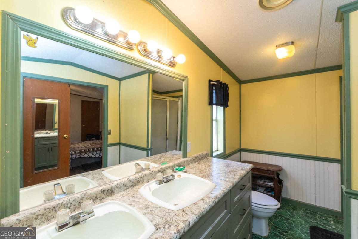3547 Chapel Lane Blackshear, GA 31516 - Photo 18 of 33 a bathroom with a granite countertop sink a toilet a mirror and shower