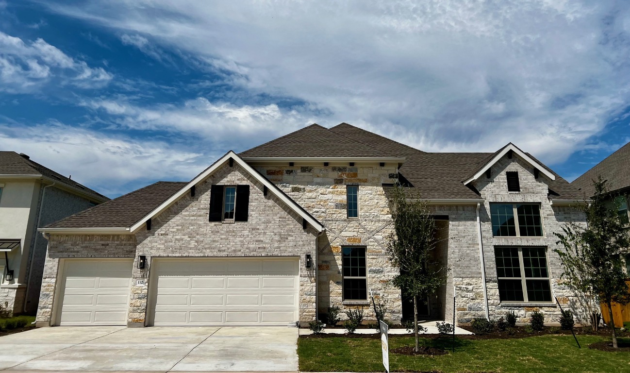 View of front facade featuring roof with shingles, driveway, stone siding, and an attached garage