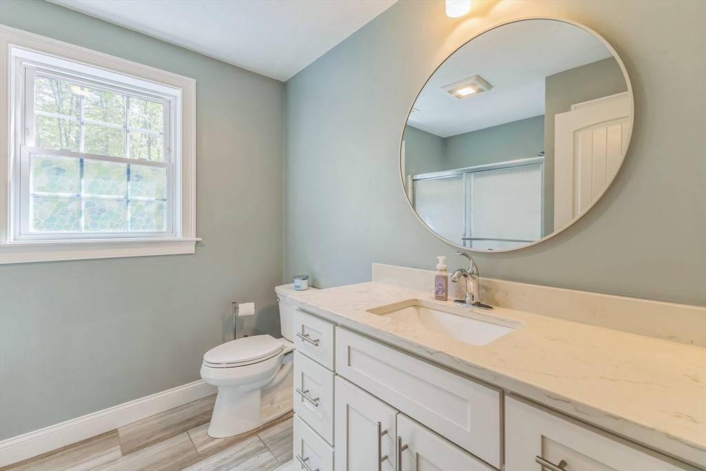 82 Sutton Street Uxbridge, MA 01569 - Photo 20 of 31 a bathroom with a toilet a sink a mirror and a window