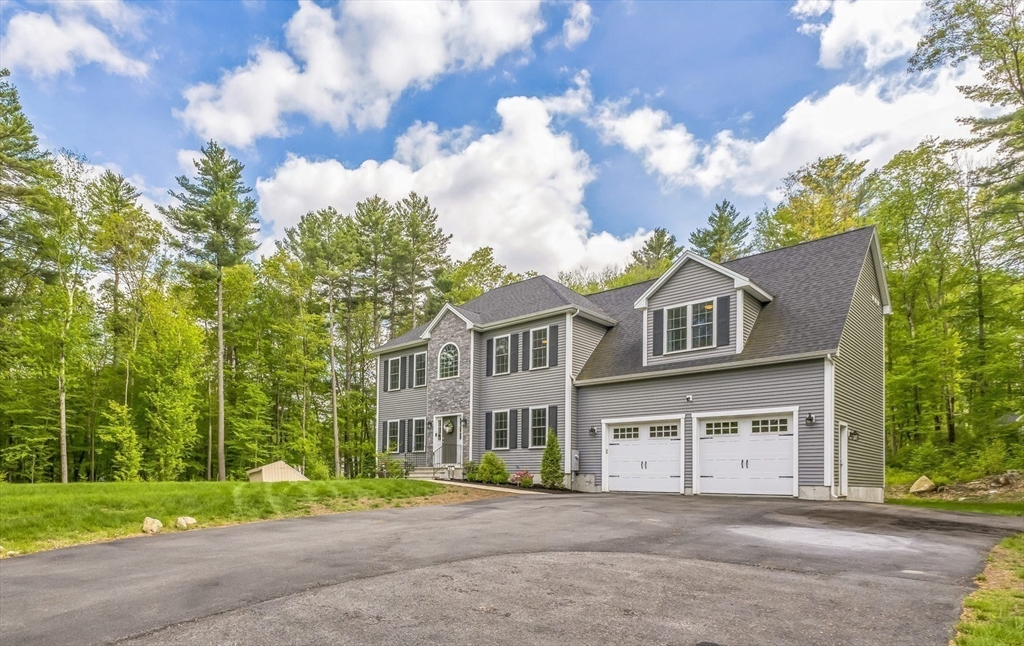 82 Sutton Street Uxbridge, MA 01569 - Photo 2 of 31 a front view of a house with a garden and trees