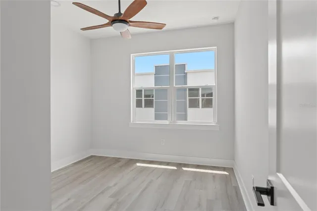 a view of an empty room with a window and wooden floor
