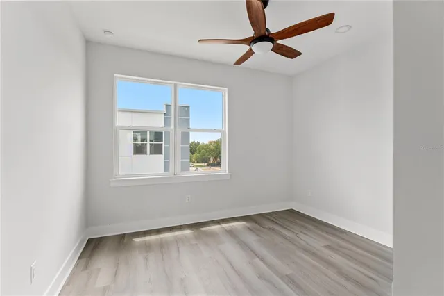 an empty room with a window and a ceiling fan