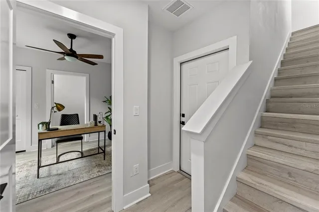 a view of a hallway to a livingroom with wooden floor and furniture