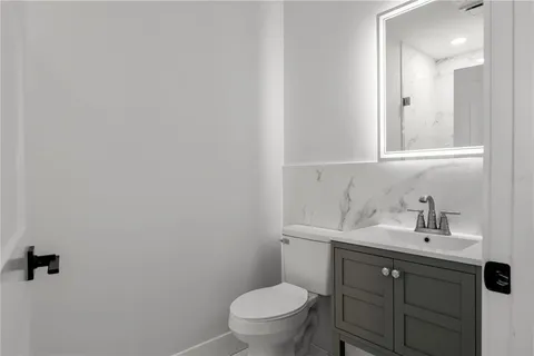 a bathroom with a toilet a sink a vanity and mirror