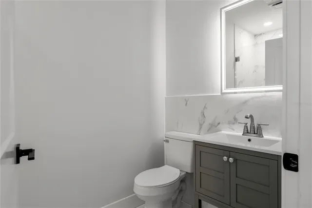 a bathroom with a toilet a sink a vanity and mirror