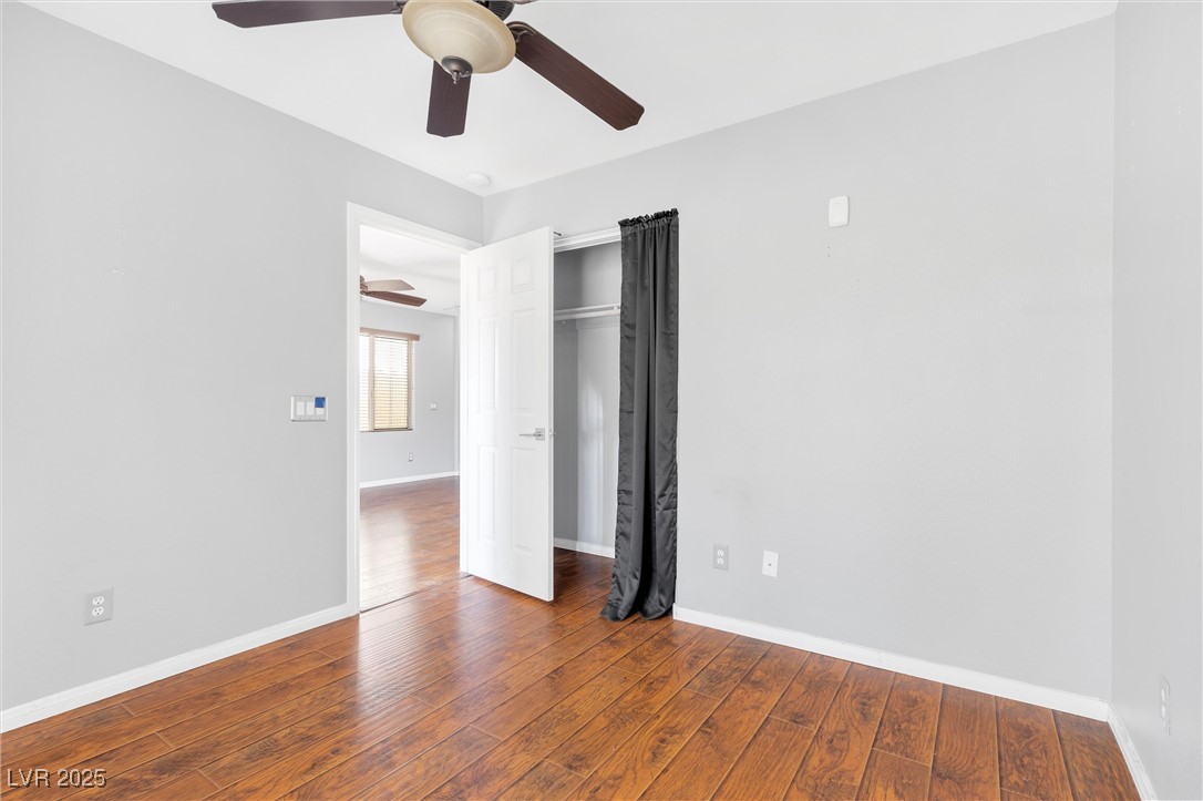 9617 Sharp Horn Court Las Vegas, NV 89149 - Photo 16 of 27 Unfurnished bedroom featuring wood-type flooring, a ceiling fan, a closet, and baseboards
