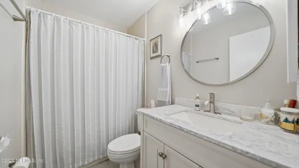 a bathroom with a granite countertop sink a toilet and a mirror