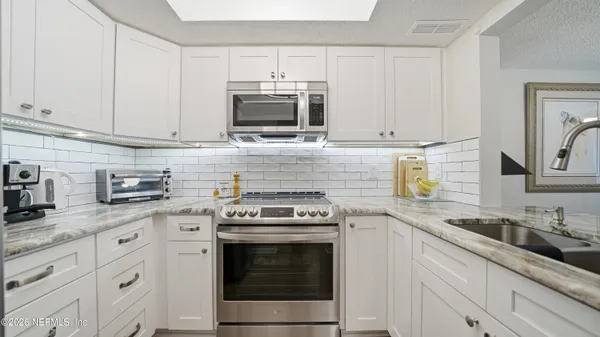 a kitchen with granite countertop white cabinets and stainless steel appliances