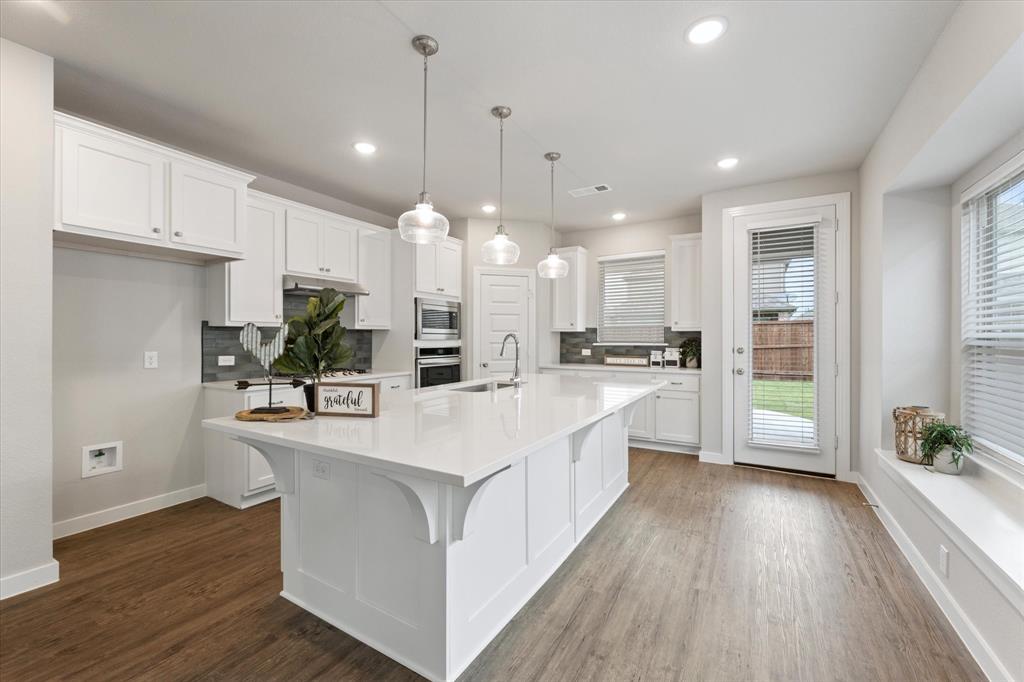 a large white kitchen with kitchen island a white cabinets and wooden floor