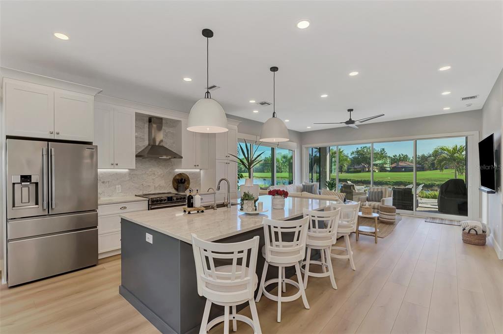 561 Fallbrook Drive Venice, FL 34292 - Photo 10 of 81 a kitchen with stainless steel appliances granite countertop a stove a refrigerator a sink a dining table and chairs with wooden floor