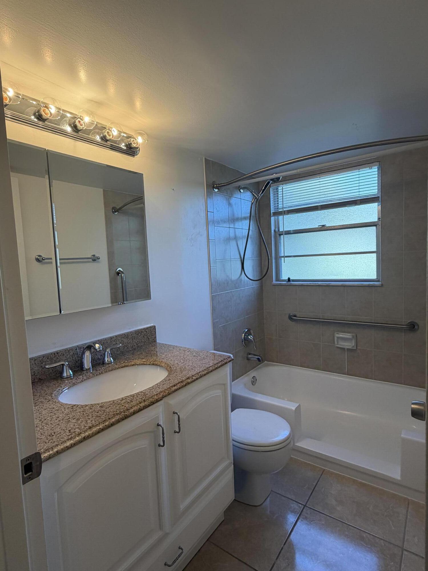 169 Suffolk F Boca Raton, FL 33434 - Photo 10 of 14 a bathroom with a granite countertop sink toilet a large mirror and bathtub