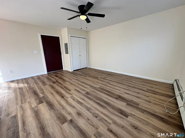a view of empty room with wooden floor and fan